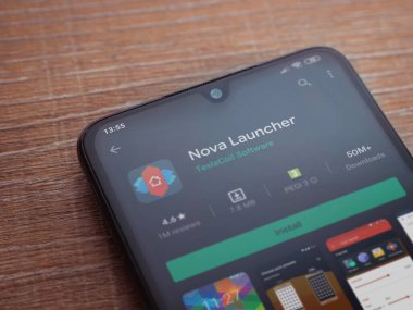 Lod, Israel - 8 Temmuz 2020: Nova Launcher uygulaması oyun mağazası sayfası ahşap arka planda siyah bir cep telefonu ekranında. Üst görünüm düzlüğü kopyalama alanı ile yatıyordu.