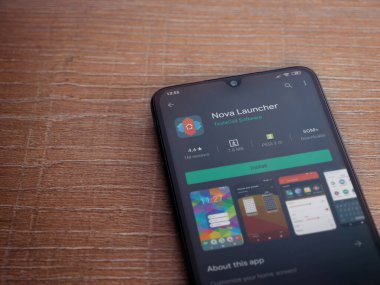 Lod, Israel - 8 Temmuz 2020: Nova Launcher uygulaması oyun mağazası sayfası ahşap arka planda siyah bir cep telefonu ekranında. Üst görünüm düzlüğü kopyalama alanı ile yatıyordu.