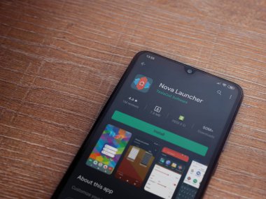 Lod, Israel - 8 Temmuz 2020: Nova Launcher uygulaması oyun mağazası sayfası ahşap arka planda siyah bir cep telefonu ekranında. Üst görünüm düzlüğü kopyalama alanı ile yatıyordu.