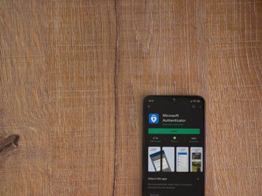 Lod, Israel - 8 Temmuz 2020: Microsoft Authenticator uygulama oyun mağazası sayfası ahşap arka planda siyah bir cep telefonu ekranında. Üst görünüm düzlüğü kopyalama alanı ile yatıyordu.