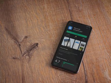 Lod, Israel - 8 Temmuz 2020: Microsoft Authenticator uygulama oyun mağazası sayfası ahşap arka planda siyah bir cep telefonu ekranında. Üst görünüm düzlüğü kopyalama alanı ile yatıyordu.