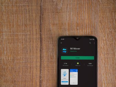 Lod, Israel - 8 Temmuz 2020: Mi Mover uygulama oyun mağazası sayfası ahşap arka planda siyah bir cep telefonunun ekranında. Üst görünüm düzlüğü kopyalama alanı ile yatıyordu.