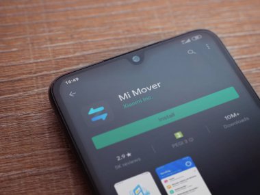 Lod, Israel - 8 Temmuz 2020: Mi Mover uygulama oyun mağazası sayfası ahşap arka planda siyah bir cep telefonunun ekranında. Üst görünüm düzlüğü kopyalama alanı ile yatıyordu.
