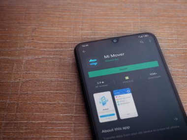 Lod, Israel - 8 Temmuz 2020: Mi Mover uygulama oyun mağazası sayfası ahşap arka planda siyah bir cep telefonunun ekranında. Üst görünüm düzlüğü kopyalama alanı ile yatıyordu.
