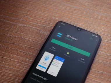 Lod, Israel - 8 Temmuz 2020: Mi Mover uygulama oyun mağazası sayfası ahşap arka planda siyah bir cep telefonunun ekranında. Üst görünüm düzlüğü kopyalama alanı ile yatıyordu.