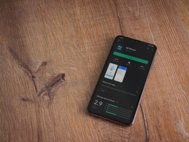 Lod, Israel - 8 Temmuz 2020: Mi Mover uygulama oyun mağazası sayfası ahşap arka planda siyah bir cep telefonunun ekranında. Üst görünüm düzlüğü kopyalama alanı ile yatıyordu.