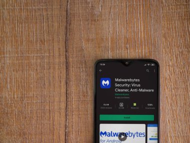 Lod, Israel - 8 Temmuz 2020: Malwarebytes Security uygulama oyun mağazası sayfası ahşap arka planda siyah bir cep telefonu sergilenmektedir. Üst görünüm düzlüğü kopyalama alanı ile yatıyordu.
