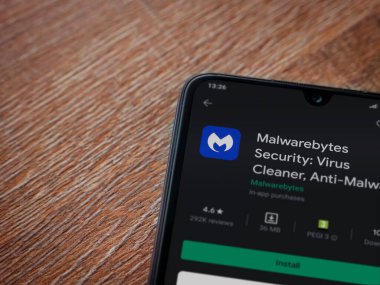 Lod, Israel - 8 Temmuz 2020: Malwarebytes Security uygulama oyun mağazası sayfası ahşap arka planda siyah bir cep telefonu sergilenmektedir. Üst görünüm düzlüğü kopyalama alanı ile yatıyordu.