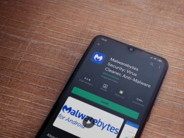 Lod, Israel - 8 Temmuz 2020: Malwarebytes Security uygulama oyun mağazası sayfası ahşap arka planda siyah bir cep telefonu sergilenmektedir. Üst görünüm düzlüğü kopyalama alanı ile yatıyordu.