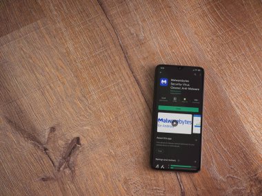 Lod, Israel - 8 Temmuz 2020: Malwarebytes Security uygulama oyun mağazası sayfası ahşap arka planda siyah bir cep telefonu sergilenmektedir. Üst görünüm düzlüğü kopyalama alanı ile yatıyordu.