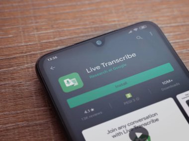Lod, Israel - 8 Temmuz 2020: Ahşap arka planda siyah bir cep telefonu ekranında Live Transcribe uygulaması oyun mağazası sayfası. Üst görünüm düzlüğü kopyalama alanı ile yatıyordu.