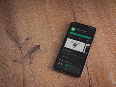 Lod, Israel - 8 Temmuz 2020: Ahşap arka planda siyah bir cep telefonu ekranında Live Transcribe uygulaması oyun mağazası sayfası. Üst görünüm düzlüğü kopyalama alanı ile yatıyordu.