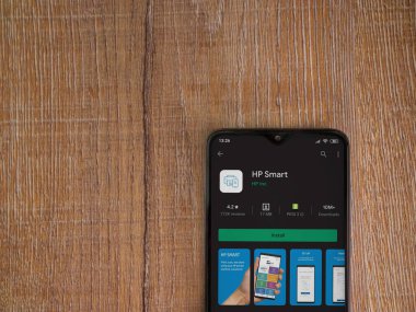 Lod, Israel - 8 Temmuz 2020: HP Smart uygulama oyun mağazası sayfası ahşap arka planda siyah bir cep telefonunun ekranında. Üst görünüm düzlüğü kopyalama alanı ile yatıyordu.