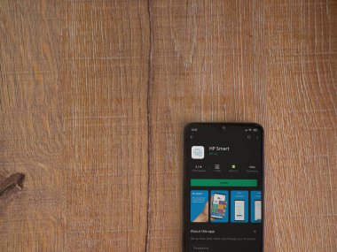 Lod, Israel - 8 Temmuz 2020: HP Smart uygulama oyun mağazası sayfası ahşap arka planda siyah bir cep telefonunun ekranında. Üst görünüm düzlüğü kopyalama alanı ile yatıyordu.