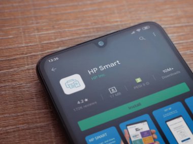Lod, Israel - 8 Temmuz 2020: HP Smart uygulama oyun mağazası sayfası ahşap arka planda siyah bir cep telefonunun ekranında. Üst görünüm düzlüğü kopyalama alanı ile yatıyordu.