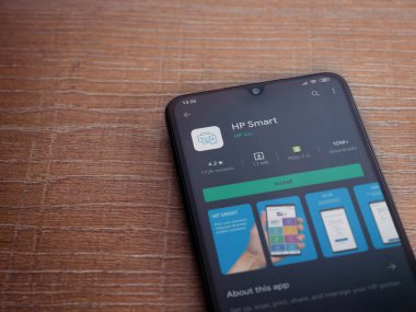 Lod, Israel - 8 Temmuz 2020: HP Smart uygulama oyun mağazası sayfası ahşap arka planda siyah bir cep telefonunun ekranında. Üst görünüm düzlüğü kopyalama alanı ile yatıyordu.