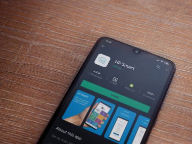 Lod, Israel - 8 Temmuz 2020: HP Smart uygulama oyun mağazası sayfası ahşap arka planda siyah bir cep telefonunun ekranında. Üst görünüm düzlüğü kopyalama alanı ile yatıyordu.