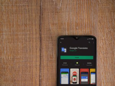 Lod, Israel - 8 Temmuz 2020: Google Translate uygulama oyun mağazası sayfası ahşap arka planda siyah bir cep telefonunun ekranında. Üst görünüm düzlüğü kopyalama alanı ile yatıyordu.