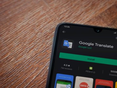 Lod, Israel - 8 Temmuz 2020: Google Translate uygulama oyun mağazası sayfası ahşap arka planda siyah bir cep telefonunun ekranında. Üst görünüm düzlüğü kopyalama alanı ile yatıyordu.
