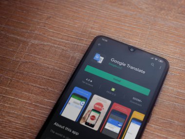 Lod, Israel - 8 Temmuz 2020: Google Translate uygulama oyun mağazası sayfası ahşap arka planda siyah bir cep telefonunun ekranında. Üst görünüm düzlüğü kopyalama alanı ile yatıyordu.