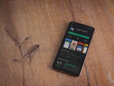 Lod, Israel - 8 Temmuz 2020: Google Translate uygulama oyun mağazası sayfası ahşap arka planda siyah bir cep telefonunun ekranında. Üst görünüm düzlüğü kopyalama alanı ile yatıyordu.