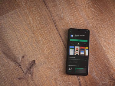 Lod, Israel - 8 Temmuz 2020: Google Translate uygulama oyun mağazası sayfası ahşap arka planda siyah bir cep telefonunun ekranında. Üst görünüm düzlüğü kopyalama alanı ile yatıyordu.