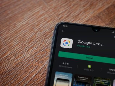 Lod, Israel - 8 Temmuz 2020: Google Lens uygulama oyun mağazası sayfası ahşap arka planda siyah bir cep telefonu ekranında. Üst görünüm düzlüğü kopyalama alanı ile yatıyordu.