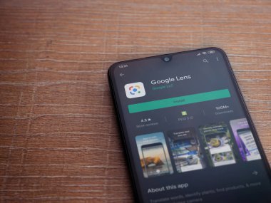 Lod, Israel - 8 Temmuz 2020: Google Lens uygulama oyun mağazası sayfası ahşap arka planda siyah bir cep telefonu ekranında. Üst görünüm düzlüğü kopyalama alanı ile yatıyordu.