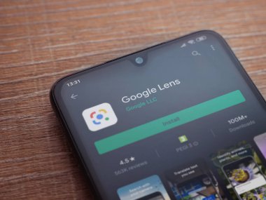 Lod, Israel - 8 Temmuz 2020: Google Lens uygulama oyun mağazası sayfası ahşap arka planda siyah bir cep telefonu ekranında. Üst görünüm düzlüğü kopyalama alanı ile yatıyordu.