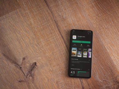Lod, Israel - 8 Temmuz 2020: Google Lens uygulama oyun mağazası sayfası ahşap arka planda siyah bir cep telefonu ekranında. Üst görünüm düzlüğü kopyalama alanı ile yatıyordu.