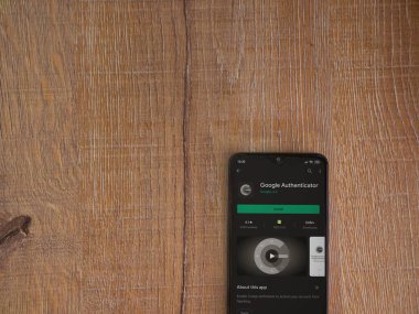 Lod, Israel - 8 Temmuz 2020: Google Authenticator uygulaması oyun mağazası sayfası ahşap arka planda siyah bir cep telefonu ekranında. Üst görünüm düzlüğü kopyalama alanı ile yatıyordu.