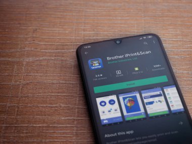 Lod, Israel - 8 Temmuz 2020: Kardeş iPrint & Scan uygulama oyun mağazası sayfası ahşap arka planda siyah bir cep telefonu görüntüsü. Üst görünüm düzlüğü kopyalama alanı ile yatıyordu.