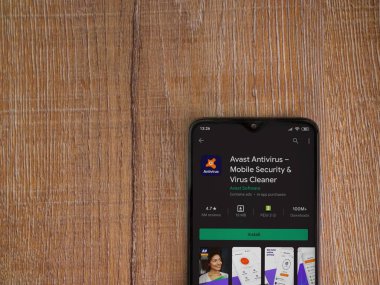 Lod, Israel - 8 Temmuz 2020: Antivirüs uygulaması oyun mağazası sayfasında ahşap arka planda siyah bir cep telefonu görüntüsü. Üst görünüm düzlüğü kopyalama alanı ile yatıyordu.