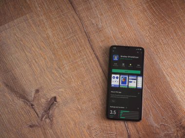 Lod, Israel - 8 Temmuz 2020: Kardeş iPrint & Scan uygulama oyun mağazası sayfası ahşap arka planda siyah bir cep telefonu görüntüsü. Üst görünüm düzlüğü kopyalama alanı ile yatıyordu.