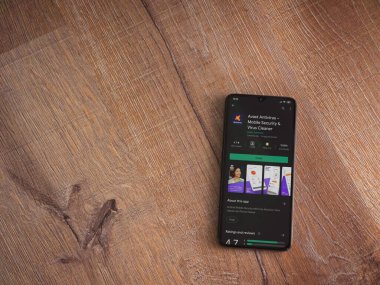 Lod, Israel - 8 Temmuz 2020: Antivirüs uygulaması oyun mağazası sayfasında ahşap arka planda siyah bir cep telefonu görüntüsü. Üst görünüm düzlüğü kopyalama alanı ile yatıyordu.