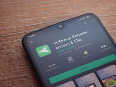 Lod, Israel - 8 Temmuz 2020: Airdroid uygulama oyun mağazası sayfası ahşap arka planda siyah bir cep telefonunun ekranında. Üst görünüm düzlüğü kopyalama alanı ile yatıyordu.