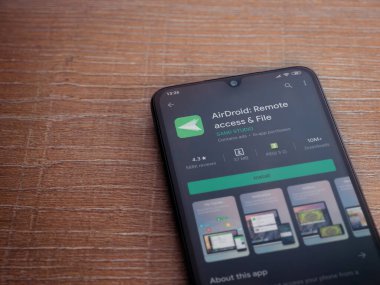 Lod, Israel - 8 Temmuz 2020: Airdroid uygulama oyun mağazası sayfası ahşap arka planda siyah bir cep telefonunun ekranında. Üst görünüm düzlüğü kopyalama alanı ile yatıyordu.