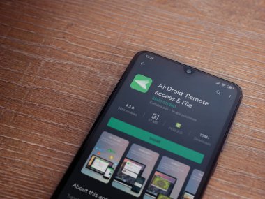 Lod, Israel - 8 Temmuz 2020: Airdroid uygulama oyun mağazası sayfası ahşap arka planda siyah bir cep telefonunun ekranında. Üst görünüm düzlüğü kopyalama alanı ile yatıyordu.