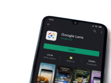 Lod, Israel - 8 Temmuz 2020: Google Lens uygulaması oyun mağazası sayfası beyaz arkaplanda izole edilmiş siyah bir cep telefonu ekranında. Üst görünüm düzlüğü kopyalama alanı ile yatıyordu.