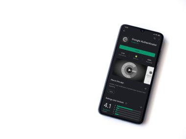 Lod, Israel - 8 Temmuz 2020: Google Authenticator uygulama oyun mağazası sayfası beyaz arkaplanda izole edilmiş siyah bir cep telefonu ekranında. Üst görünüm düzlüğü kopyalama alanı ile yatıyordu.
