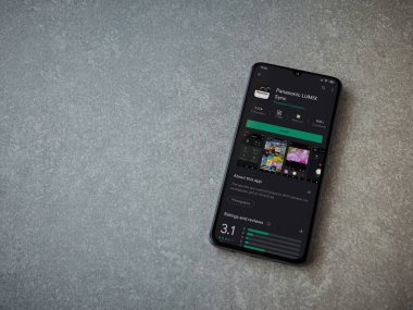 Lod, Israel - 8 Temmuz 2020: Panasonic LUMIX Sync uygulama oyun mağazası sayfası seramik taş zemin üzerinde siyah bir cep telefonu görüntüsü. Üst görünüm düzlüğü kopyalama alanı ile yatıyordu.