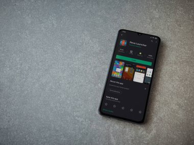 Lod, Israel - 8 Temmuz 2020: Nova Launcher uygulaması oyun mağazası sayfası seramik taş zemin üzerinde siyah bir cep telefonu görüntüsü. Üst görünüm düzlüğü kopyalama alanı ile yatıyordu.