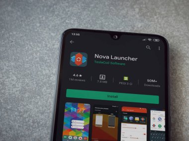 Lod, Israel - 8 Temmuz 2020: Nova Launcher uygulaması oyun mağazası sayfası seramik taş zemin üzerinde siyah bir cep telefonu görüntüsü. Üst görünüm düzlüğü kopyalama alanı ile yatıyordu.
