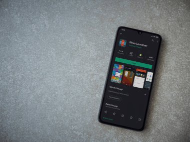 Lod, Israel - 8 Temmuz 2020: Nova Launcher uygulaması oyun mağazası sayfası seramik taş zemin üzerinde siyah bir cep telefonu görüntüsü. Üst görünüm düzlüğü kopyalama alanı ile yatıyordu.