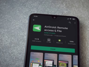 Lod, Israel - 8 Temmuz 2020: Airdroid uygulama oyun mağazası sayfası seramik taş zemin üzerinde siyah bir cep telefonu sergilenmektedir. Üst görünüm düzlüğü kopyalama alanı ile yatıyordu.