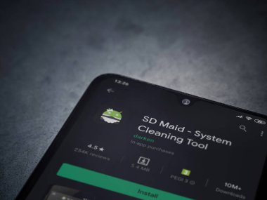 Lod, Israel - 8 Temmuz 2020: SD Maid uygulaması oyun mağazası sayfası koyu mermer taşlı arka planda siyah bir cep telefonu sergilenmektedir. Üst görünüm düzlüğü kopyalama alanı ile yatıyordu.