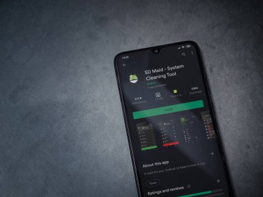 Lod, Israel - 8 Temmuz 2020: SD Maid uygulaması oyun mağazası sayfası koyu mermer taşlı arka planda siyah bir cep telefonu sergilenmektedir. Üst görünüm düzlüğü kopyalama alanı ile yatıyordu.