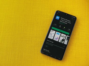 Lod, Israel - 8 Temmuz 2020: Maxthon Tarayıcı uygulama oyun mağazası sayfası sarı kumaş arka planda siyah bir cep telefonu ekranında. Üst görünüm düzlüğü kopyalama alanı ile yatıyordu.