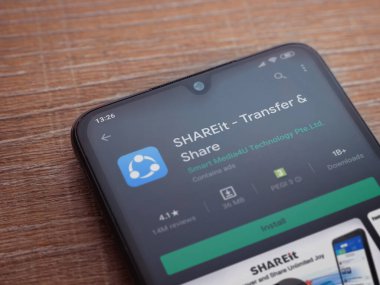 Lod, Israel - 8 Temmuz 2020: SharEit uygulaması oyun mağazası sayfası ahşap arka planda siyah bir cep telefonunun ekranında. Üst görünüm düzlüğü kopyalama alanı ile yatıyordu.
