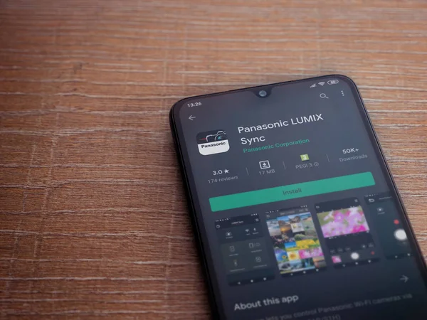 Lod, Israel - 8 Temmuz 2020: Panasonic LUMIX Sync uygulama oyun mağazası sayfası ahşap arka planda siyah bir cep telefonu görüntüsü. Üst görünüm düzlüğü kopyalama alanı ile yatıyordu.